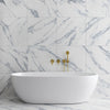 White Marble Effect Tiles with Blue Veining on Bathroom Wall behind free standing bathtub with gold features