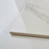 Close-up of a white carrara marble effect tile on a light gray background