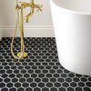 Bathroom with black hexagonal tiles, gold faucet, and white bathtub.
