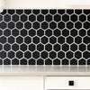 Black hexagonal tiles on a kitchen backsplash with white grout.