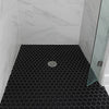 Shower with black hexagonal tiles on the floor and white walls.