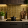 Modern kitchen with gold tiled backsplash, black cookware, and wooden cutting board.