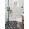 Bathroom with white tiled walls, a glass shower enclosure, and patterned floor.