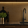 Modern kitchen with black faucet, marble countertop, and gold tile backsplash.