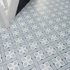 Mr Jones Pattern Light blue and white patterned ceramic floor tiles arranged in a geometric grid design, shown with a white chair leg in the top left corner.