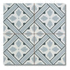 A square decorative tile with a geometric Mr Jones pattern in light blue, gray, and off-white, featuring a central floral motif and diagonal striped bands.