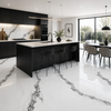 Modern kitchen with black cabinets, white and marble countertops and floor, and a dining area.