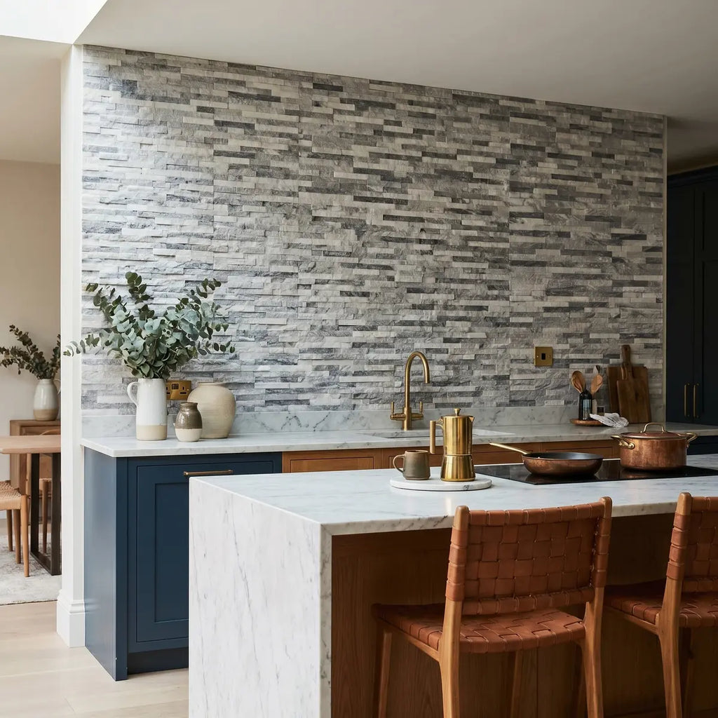 Modern kitchen with stone backsplash, marble island, and wooden chairs.