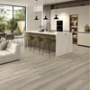 Light grey wood-look floor tiles in a modern kitchen and living room setting, showing a clean, contemporary interior design.